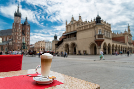 Rynek w Krakowie z widokiem na Kościół Mariacki i Sukiennice; na pierwszym planie stolik w kawiarni z kawą